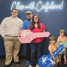 Stone Merton with a family at closing, holding a giant key